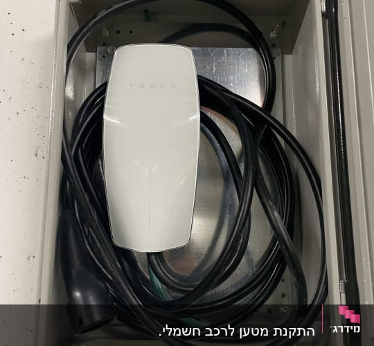 מטען טסלה עם כבל חשמלי בתוך ארון מתכת